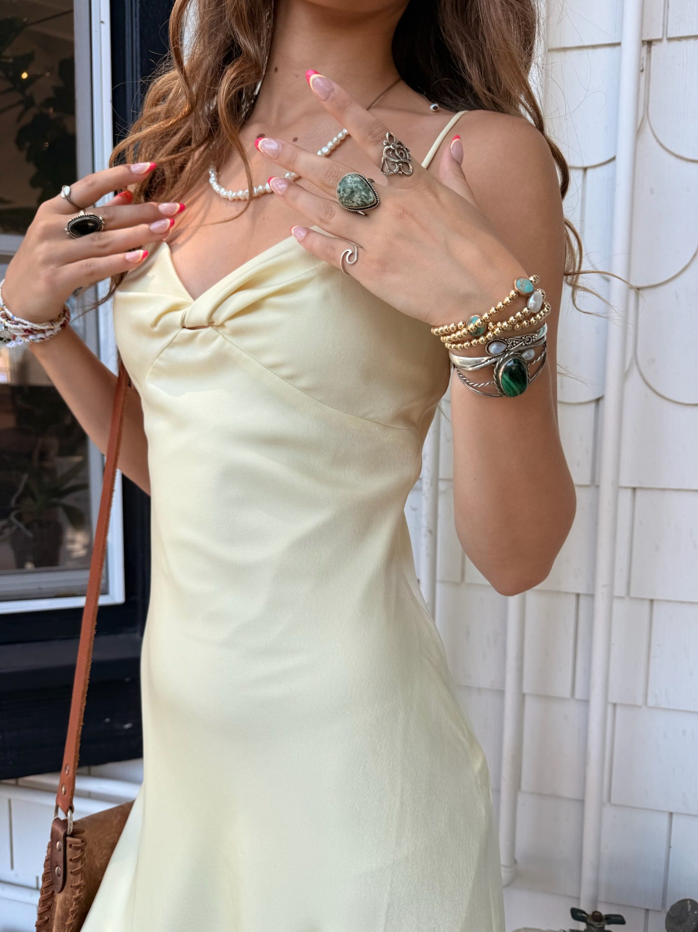 Woman wearing a light-colored dress with jewelry in an indoor setting.