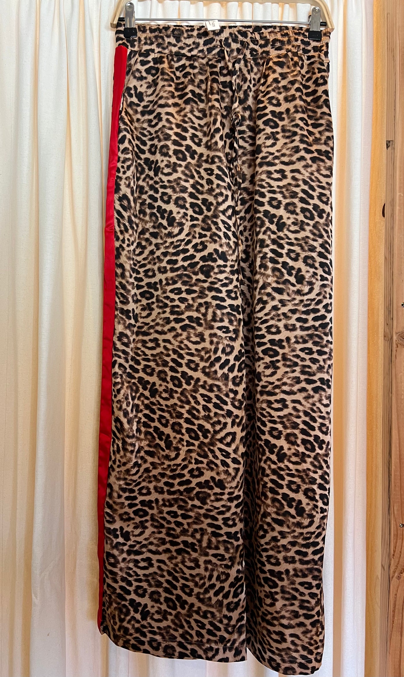 Leopard print pants on a hanger against a neutral background