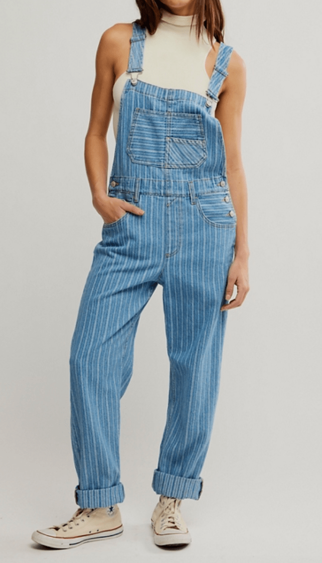Person wearing blue denim overalls on a plain background