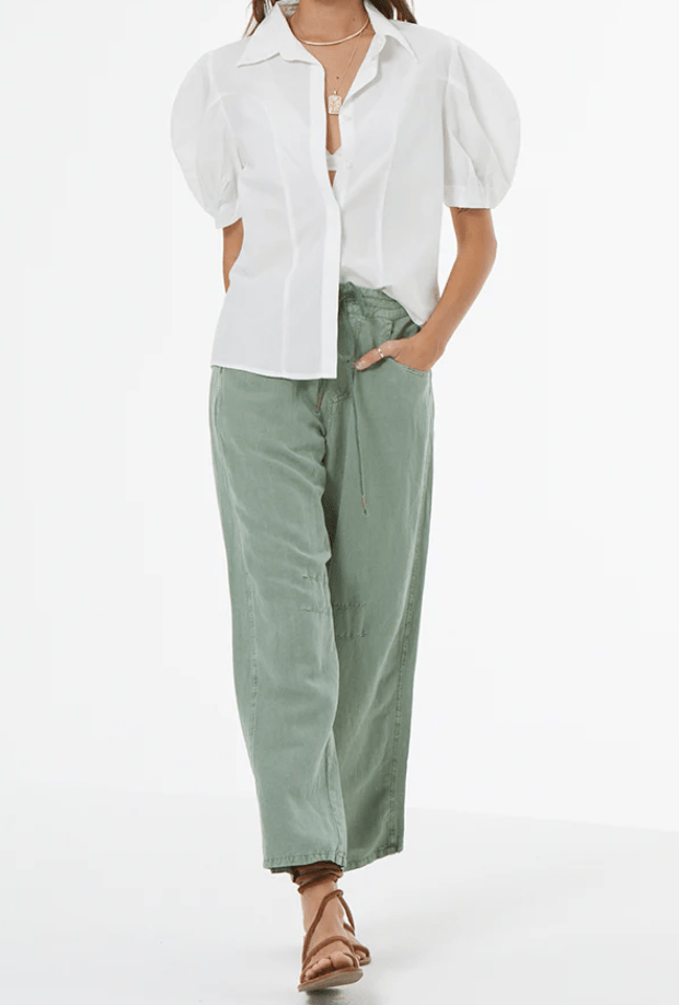 Person wearing a white blouse and green pants on a white background