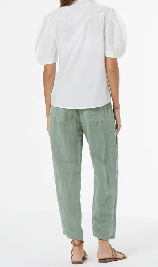 Person wearing a white top and green pants on a white background