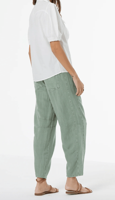 Person wearing a white shirt and green pants on a white background