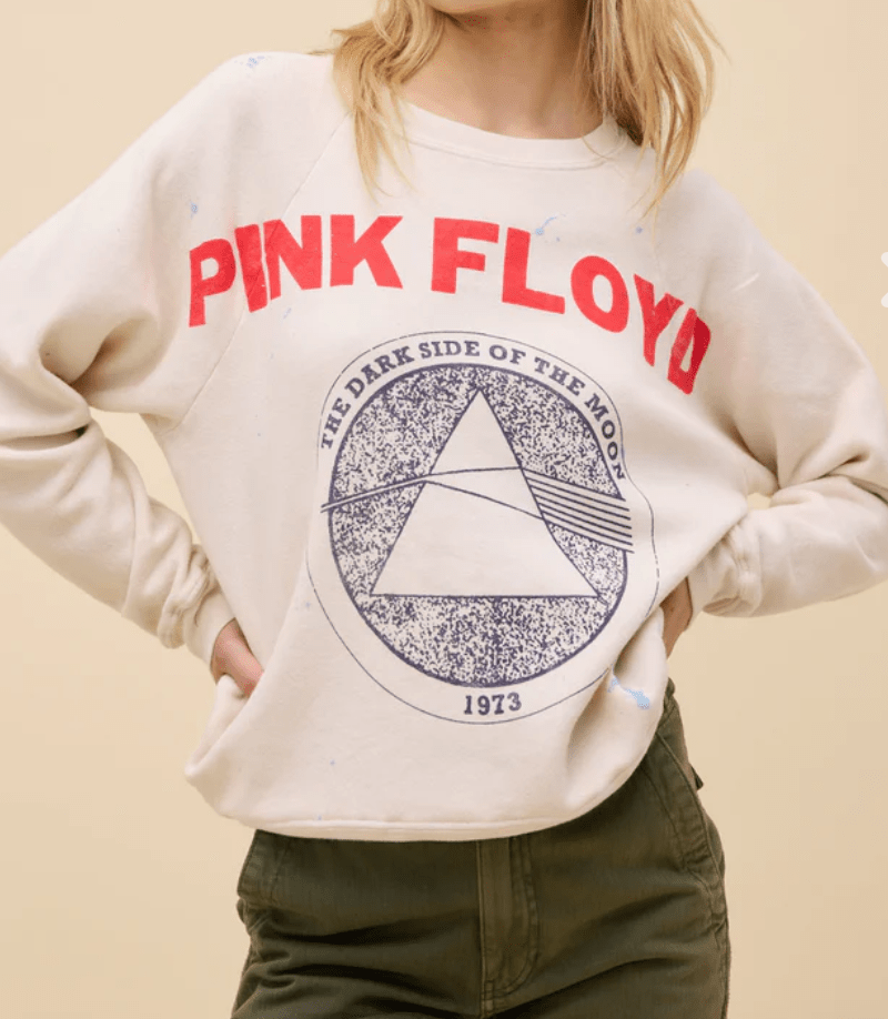 Person wearing a Pink Floyd sweatshirt with a graphic design on a beige background