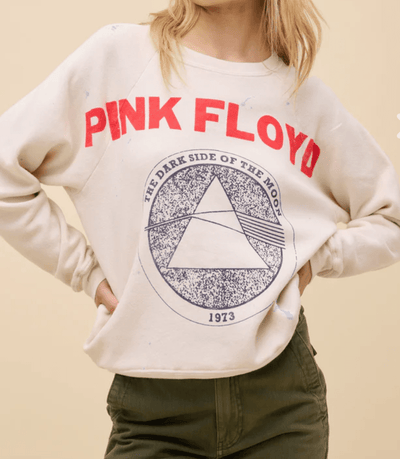 Person wearing a Pink Floyd sweatshirt with a graphic design on a beige background