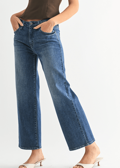 Person wearing blue jeans on a plain background