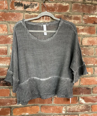 Gray knit sweater on a hanger against a brick wall
