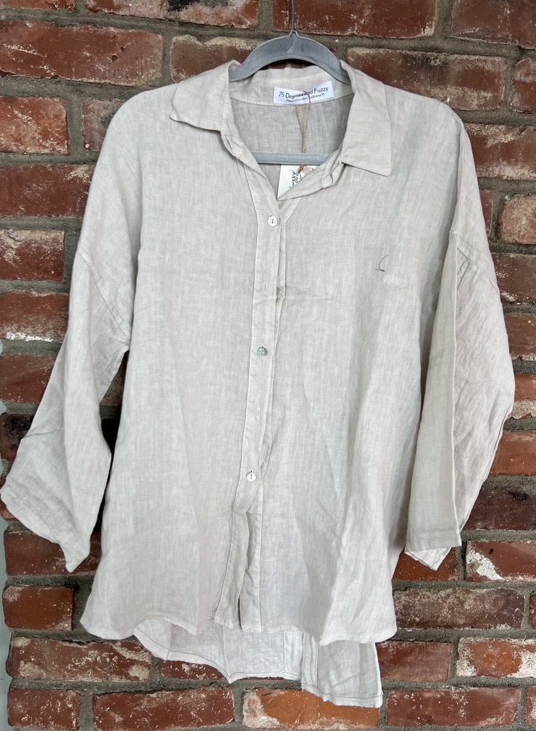 Light-colored shirt on a hanger against a brick wall
