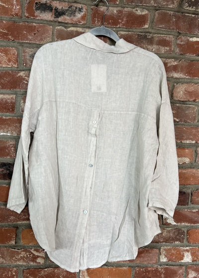 Light-colored shirt on a hanger against a brick wall